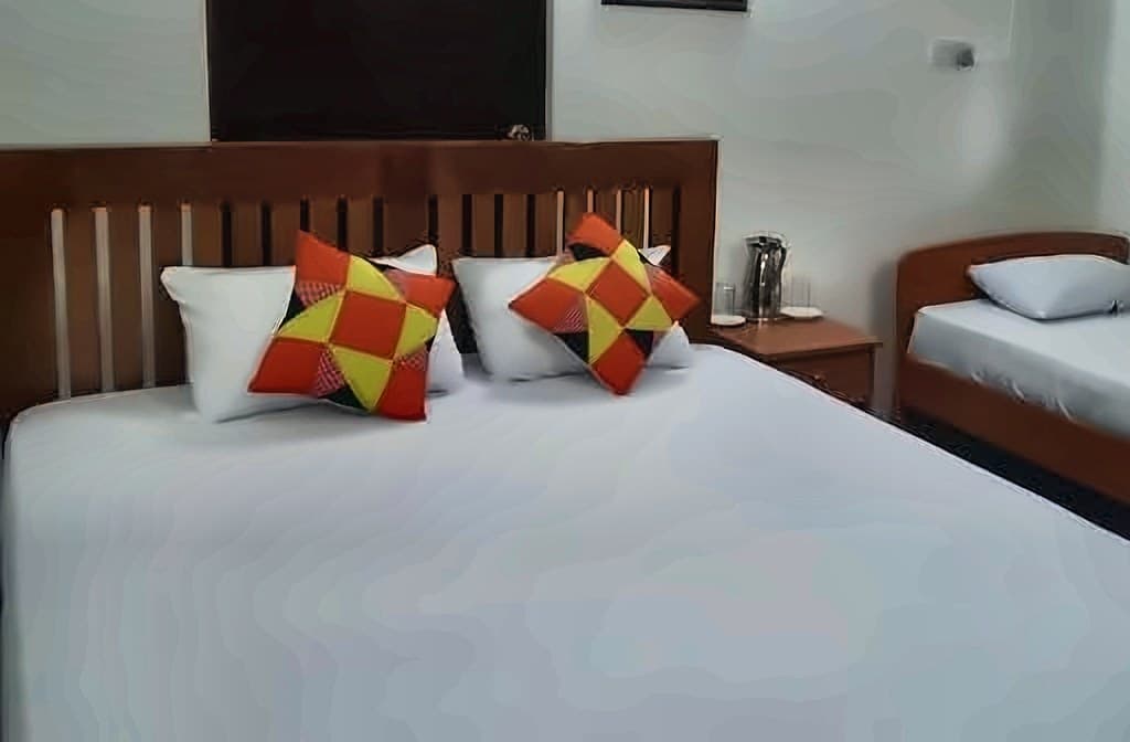 Guest room bed with red and yellow cushions and a wooden headboard